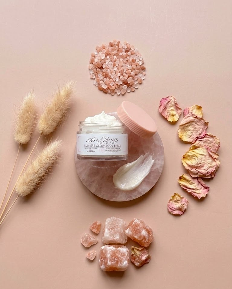 Skincare product with pink salt crystals, dried flowers, and herbs on a beige background