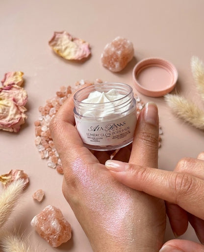 Hand holding a jar of cream with decorative elements on a light background